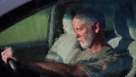 very sad man sitting in automobile dealing with depression as rain hits the windshield in slow motion