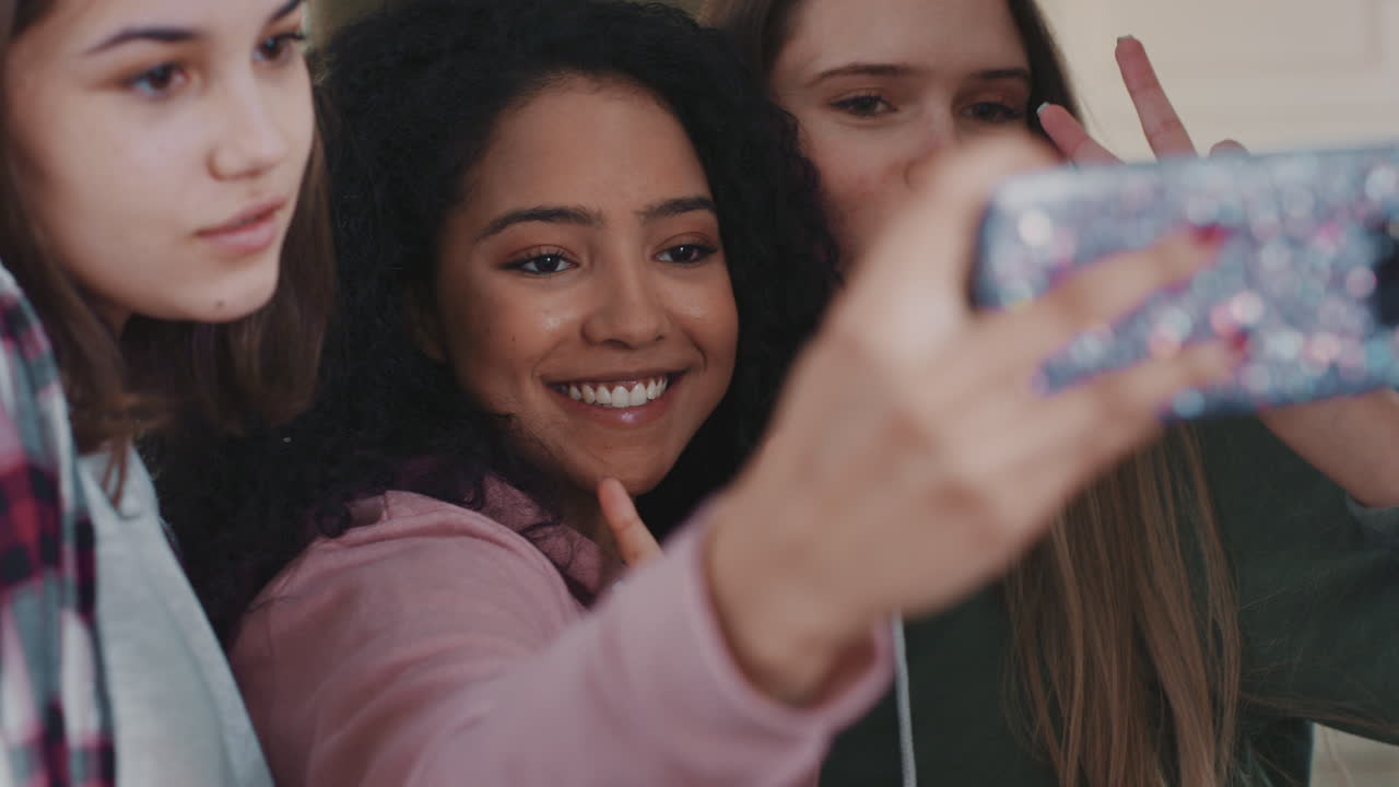 ragazze adolescenti multirazziali che scattano foto usando lo smartphone che posano facendo facce che si divertono a uscire insieme condividendo l'amicizia sui social media