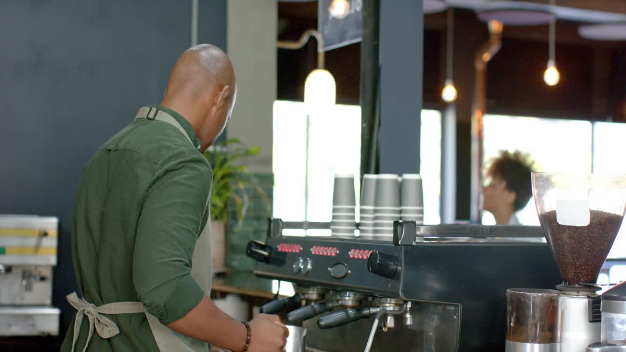 Barista che guarda verso una grande finestra, che regola la macchina per caffè espresso, blocca il portafiltro e prepara una bevanda