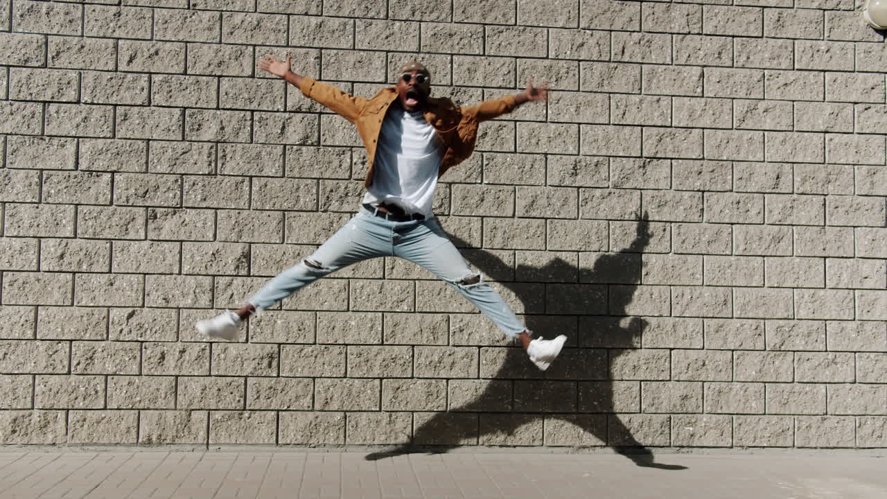 Man Dancing in Front of a Brick Wall
