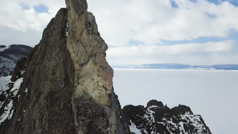 paisaje de invierno de un pico de montaña rocosa sobre un lago congelado