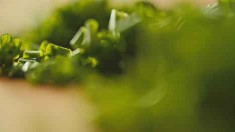 close macro shot of fresh chopped chives laying on a wooden cutting board, rotating camera