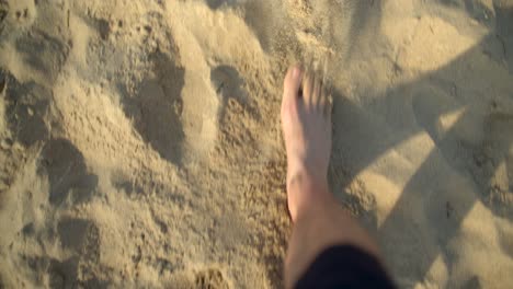 Man-legs-walking-on-a-sandy-beach-camera-tilt-down