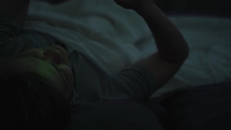 person lying in bed using smartphone at night