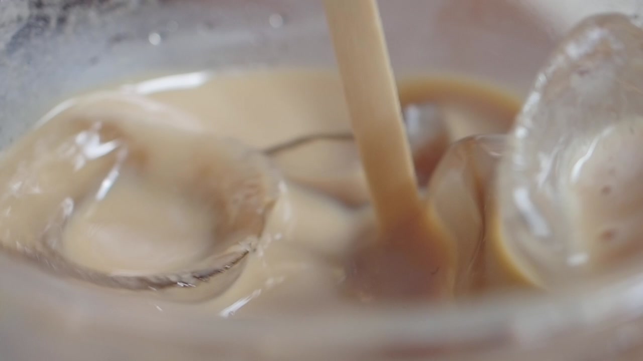 Close-up of Iced Coffee Being Stirred with a Wooden Stick