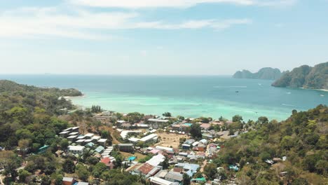 Picturesque-village-next-to-idyllic-coastline-of-Ko-Phi-Phi-Don-Island-Paradise-in-Thailand---Aerial-Slow-panoramic-shot