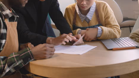 tres propietarios de pequeñas empresas multiétnicas haciendo contabilidad en su cafetería