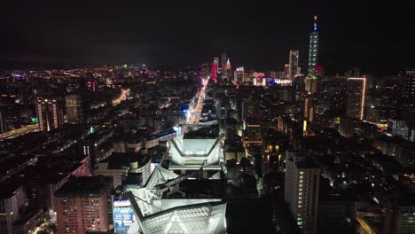 Vuelo-Aéreo-Sobre-Las-Torres-De-Taipei-En-La-Noche-Con-La-Iluminación-De-La-Torre-101-En-El-Fondo---Taipei,-Taiwán