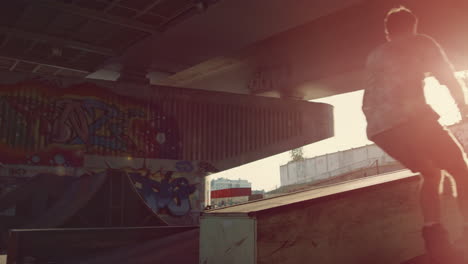 Extreme-men-training-tricks-at-skate-park-with-graffiti-on-wall.-Rider-racing.