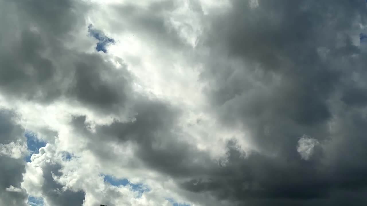 Beautiful white fluffy cumulonimbus clouds mixing and churning with darker storm clouds in timelapse mode