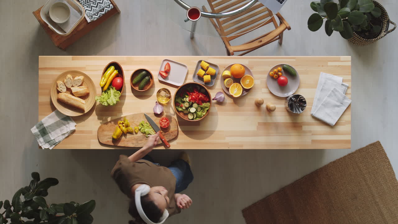 mujer cocinando ensalada y bailando en casa