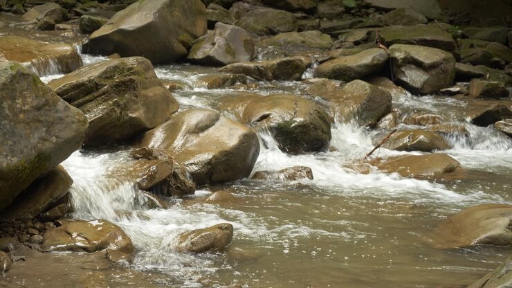 Acqua fresca e limpida che scorre tra massi marroni 4K