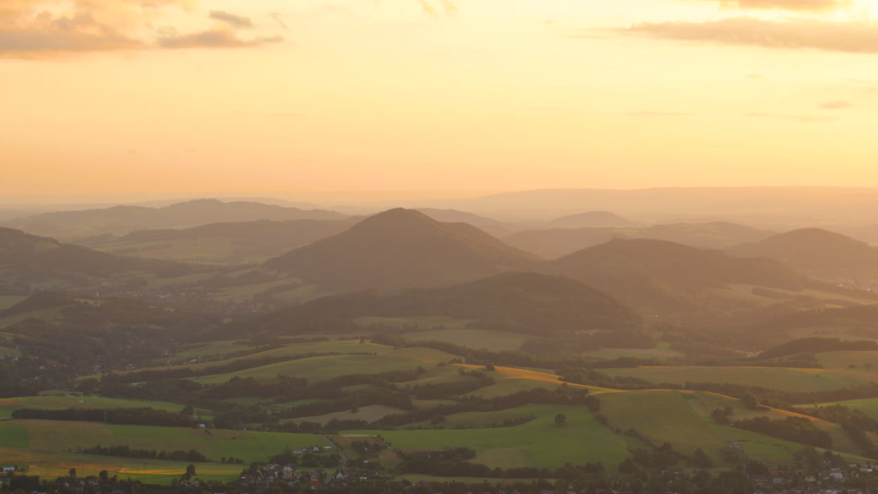 광선이 들판의 산 위에 있는 풍경을 통해 빛나고 계곡이 금으로 범람할 때 일몰 동안 산악 풍경의 전망