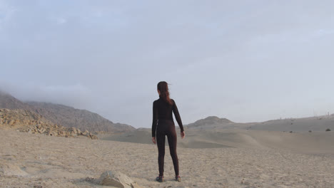 long back shot of a mysterious woman in black standing in the middle of the desert