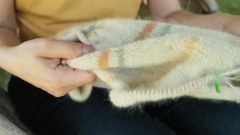 female hand knitting sweater in pastel colors stripes, close up