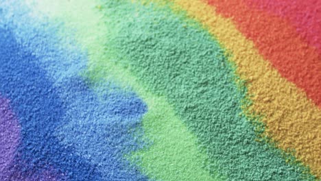 Video-of-close-up-of-rainbow-coloured-sand-grains-and-copy-space-background