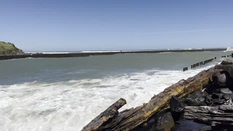 waves splashing on surfers on surfing board at the beach in patea, taranaki, new zealand