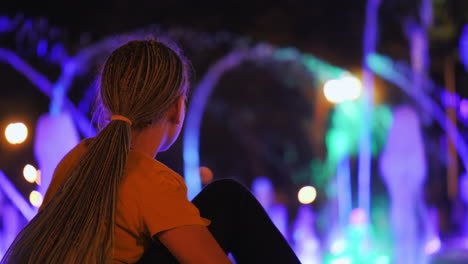 una niña mira una fuente de baile en un parque en el centro de kharkiv