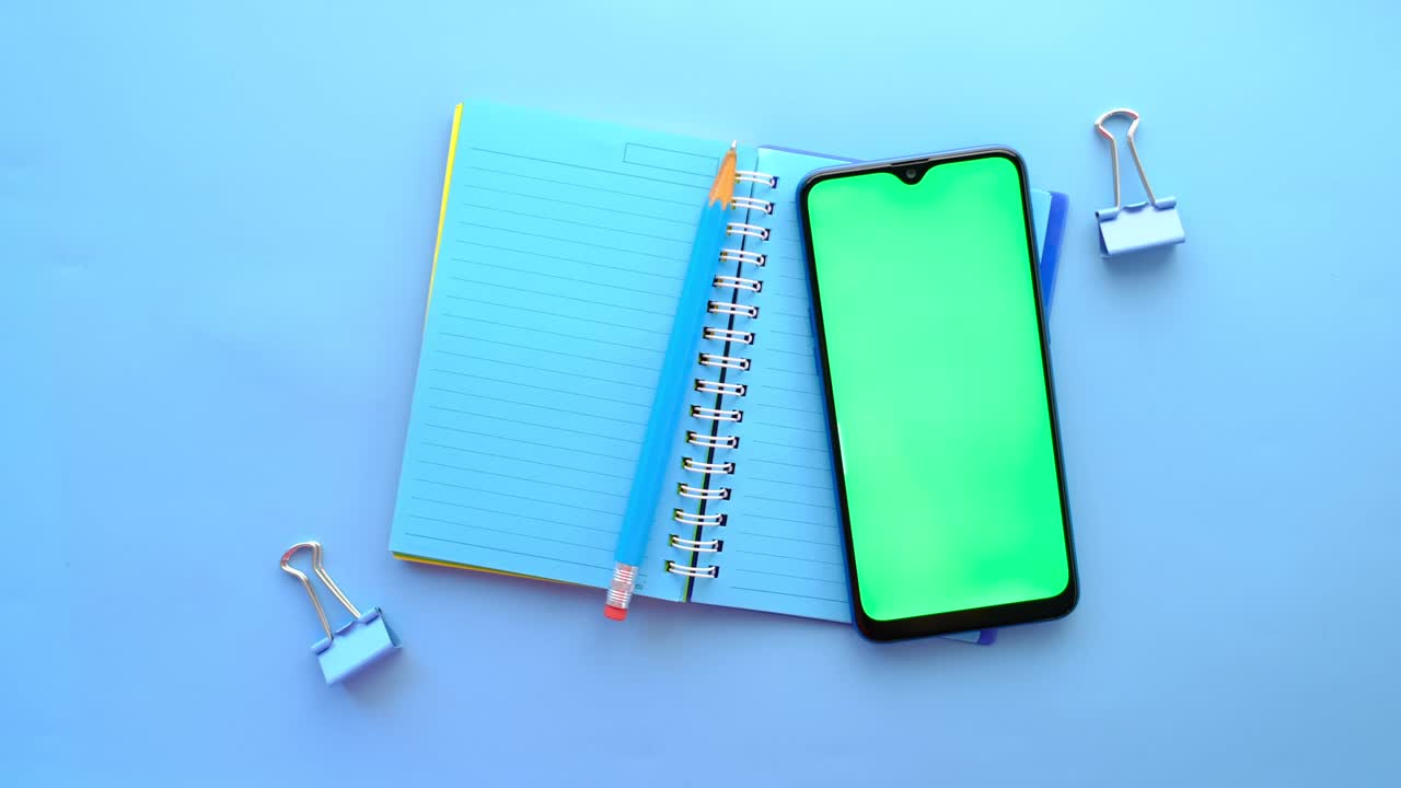 top view of smart phone and notepad on blue background