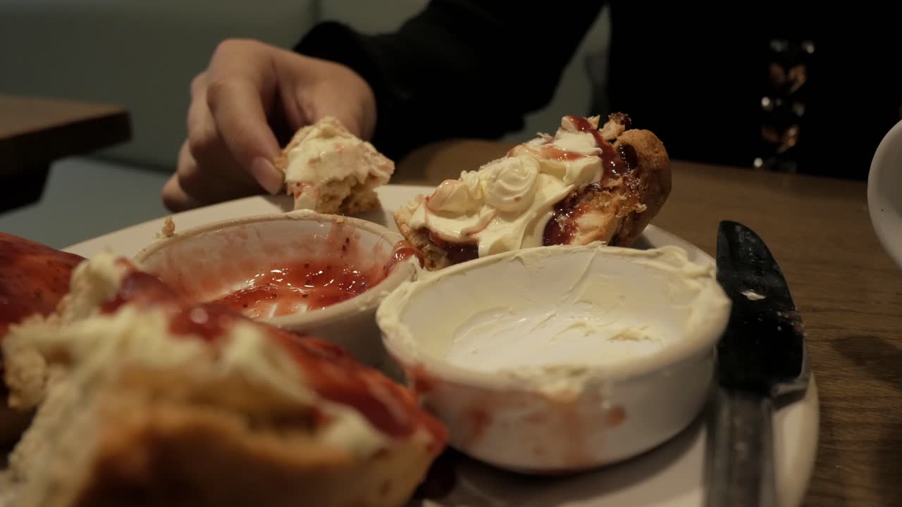 A plate of scones with clotted cream and jam, captured in a cozy dining setting
