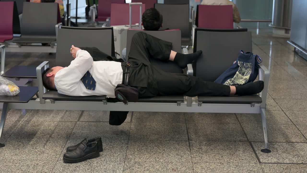 un pasajero descansa en un banco del aeropuerto en la sala de llegadas mientras usa su teléfono para pasar el tiempo en el aeropuerto internacional de hong kong