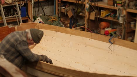 craftsman oiling wooden boat interior in boatshed