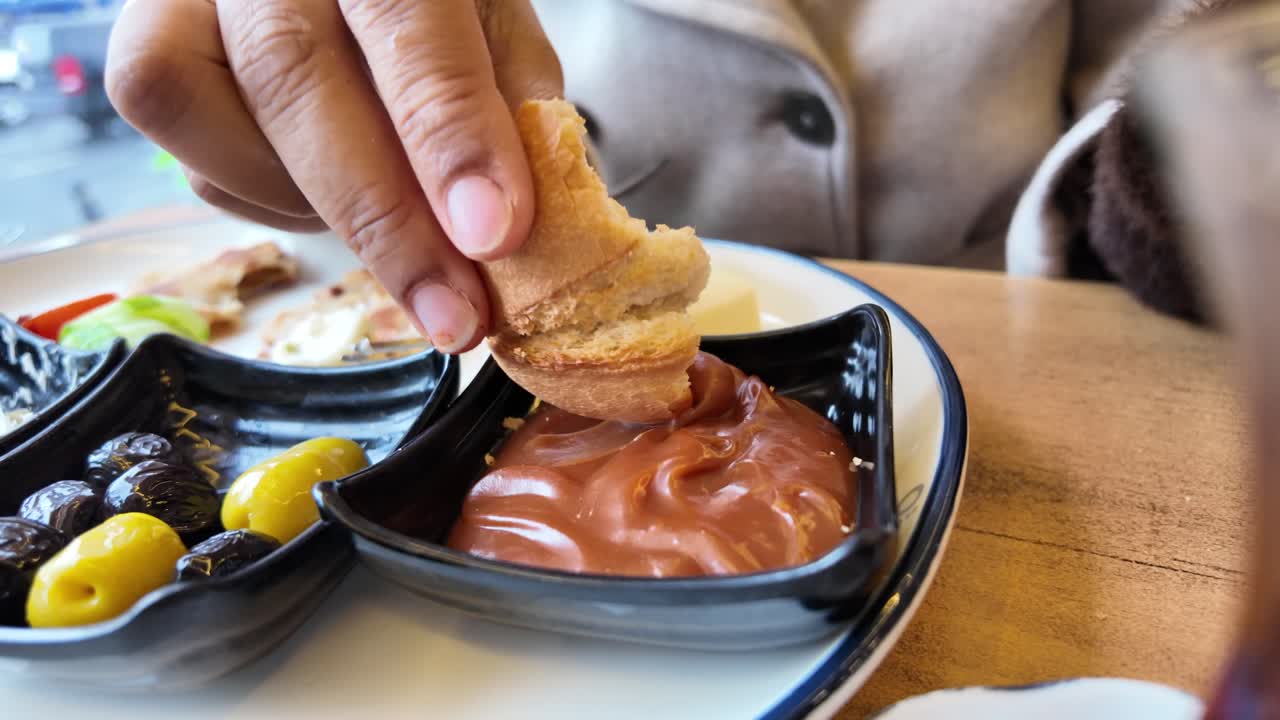 Close-Up of Hand Dipping Bread into Chocolate Spread at Breakfast