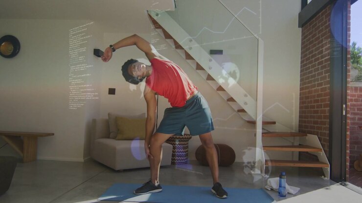 Man doing side-stretch on blue mat at home, following fitness tracker prompt, showing lens flares