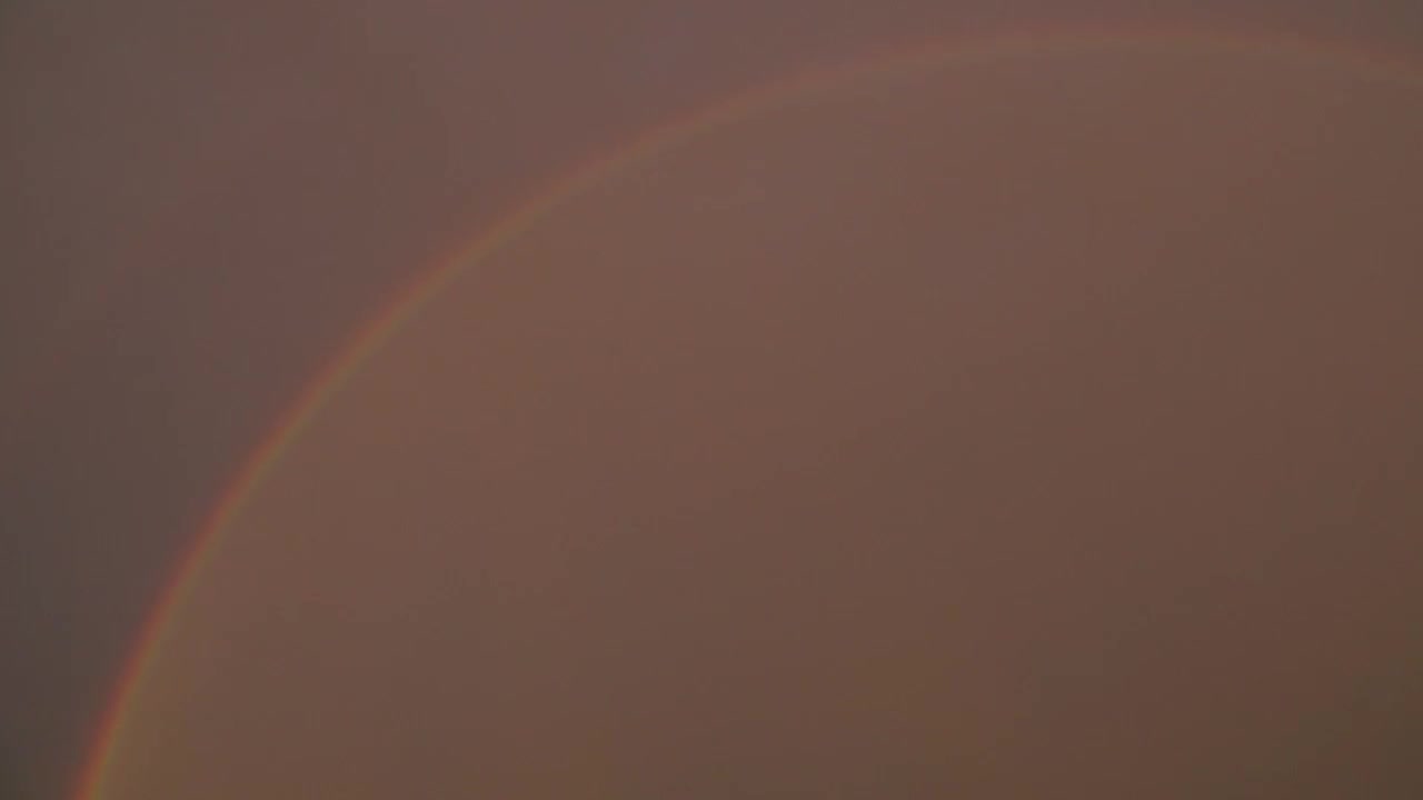 Regnbue buer over en skyet himmel. Smukt meteorologisk fænomen, der skaber en fredfyldt og farverig atmosfære i naturen