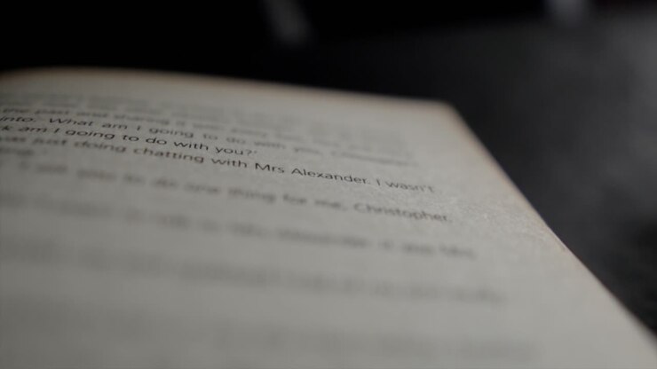 A close up macro shot tracking down the page of a novel, the shallow depth of field highlighting sentences in the story as the camera slowly moves down