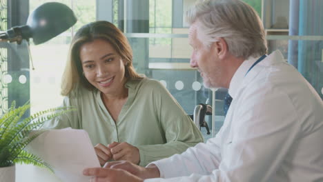 doctor in office discussing test results with female patient in wheelchair in hospital