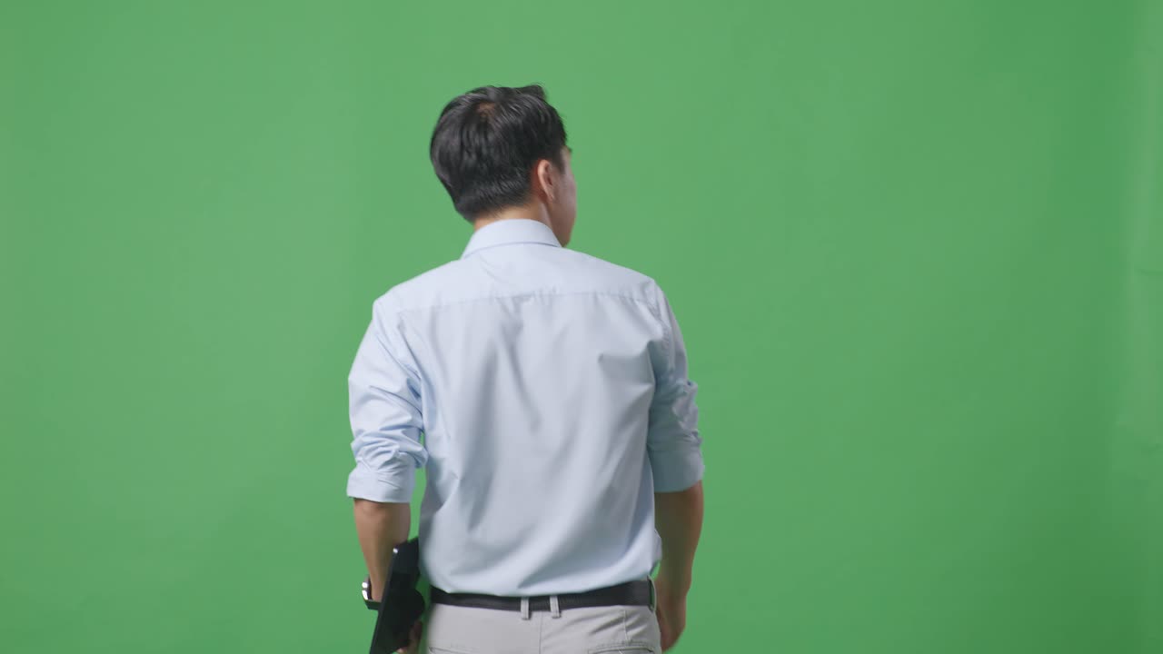 태블릿을 들고 스튜디오에서 녹색 화면 배경에서 고 있는 아시아 사업가의 뒷면