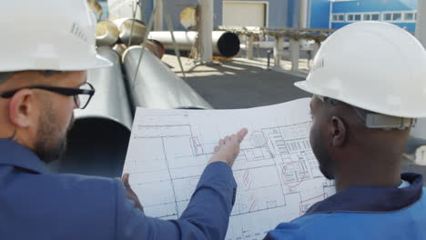 engineer and plant foreman looking at blueprint outdoors