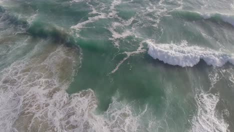 Hermosas-Olas-Del-Océano-Cerca-De-La-Costa-Agitan-El-Fondo-Arenoso,-Antena