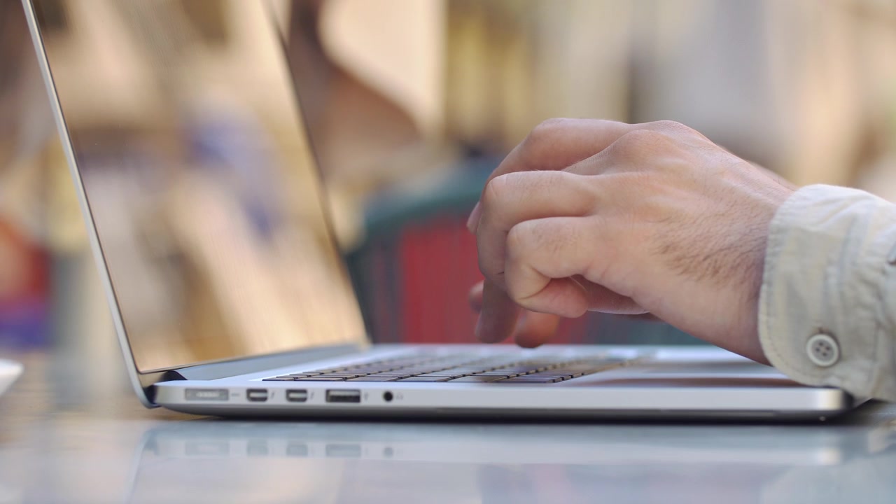 Primer plano de una persona escribiendo en el teclado de un portátil.