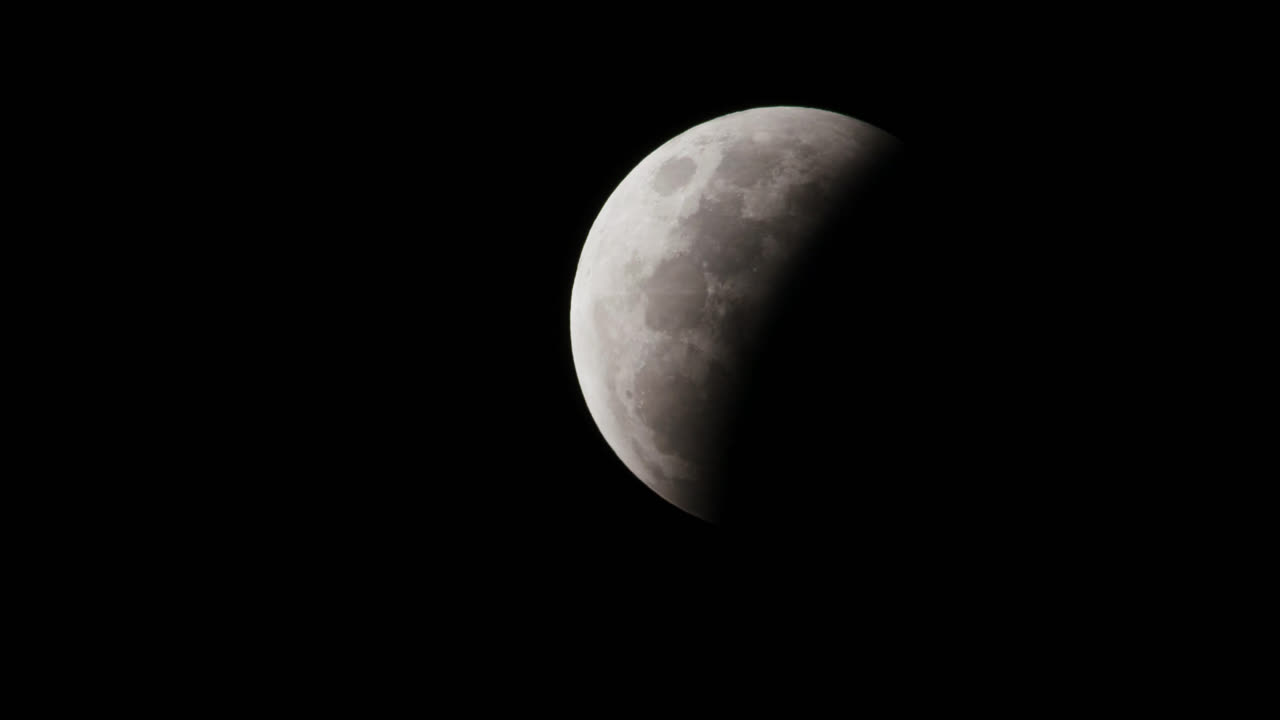 A first quarter moon at night with clear skies and half of the moon covered in light and the other in darkness