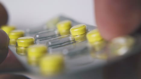 person-shows-blister-with-bright-pills-on-white-background