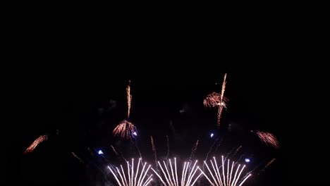 coloridos fuegos artificiales reales celebran la víspera de año nuevo con un desenfoque abstracto de brillo dorado con luces bokeh en el cielo nocturno