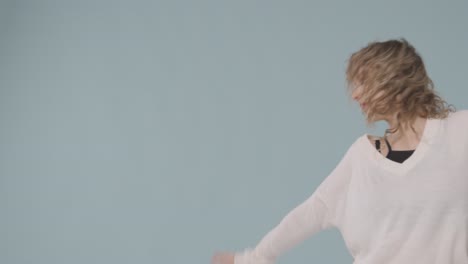 studio shot of young woman having fun dancing against blue background 2