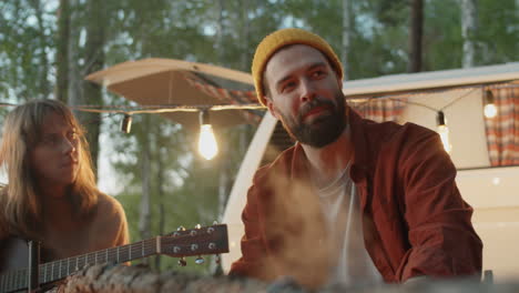 joyous man chatting with girls by campfire