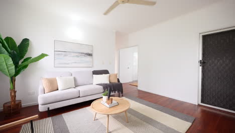 Sleek-Modern-Loungeroom-And-Grey-Beige-Rug-at-Center-of-White-Couch-Tropical-Plants-and-Abstract-Ocean-Painting