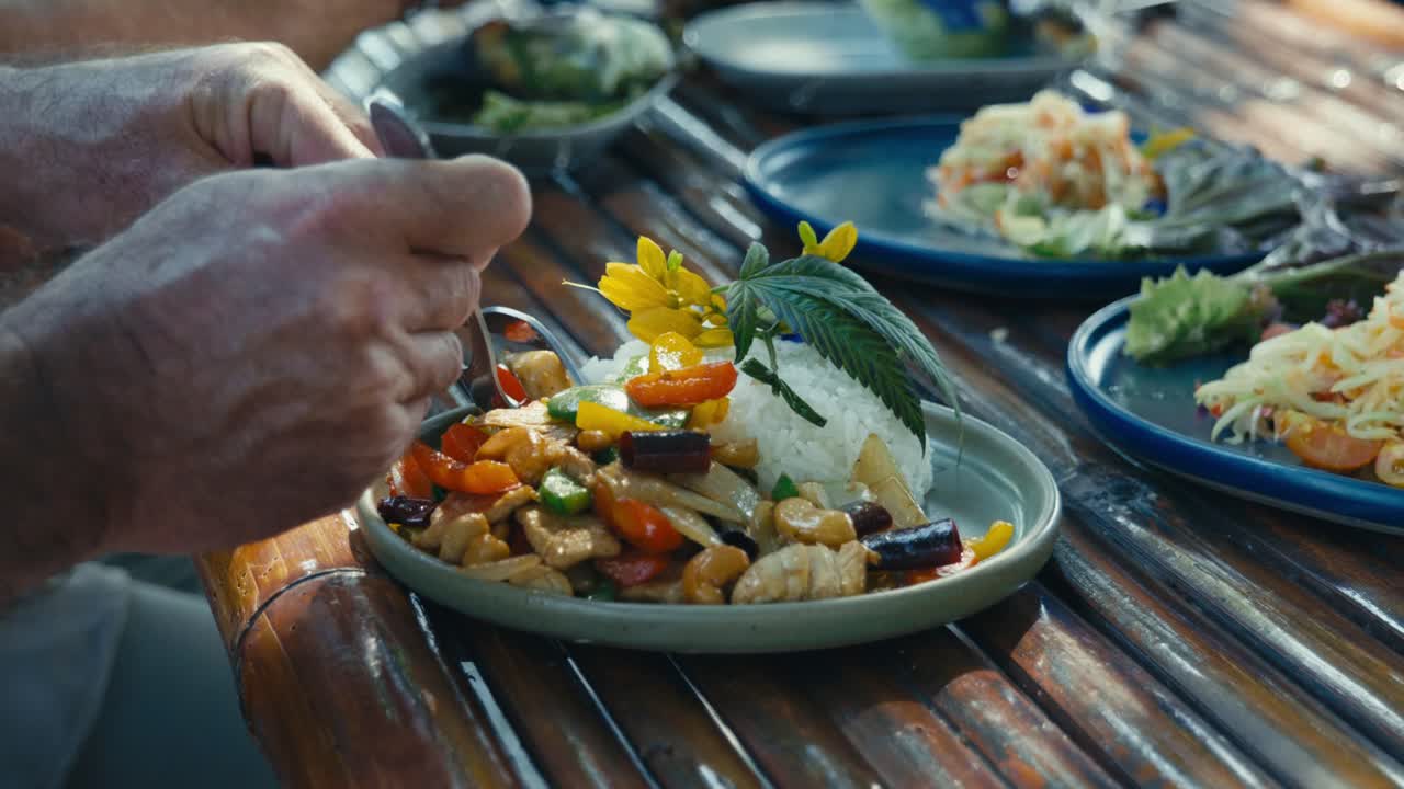 A man eats a Thai dish made with chicken, rice, and cashew nuts, enjoying a traditional meal and authentic Thai flavors