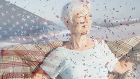 animación de la bandera de los estados unidos de américa y confeti sobre una mujer caucásica mayor en la playa