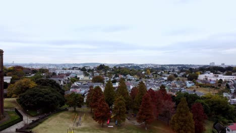 A-tranquil-park-with-colorful-autumn-trees-and-playground,-overcast-sky,-aerial-view