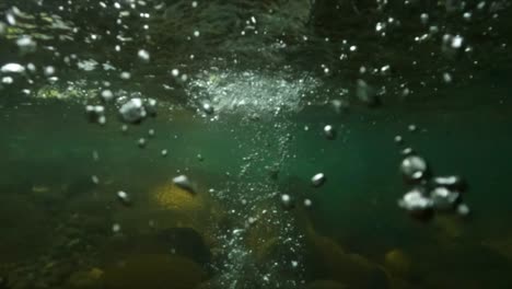 Tiro-Bajo-El-Agua-En-Cámara-Lenta-De-Una-Piedra-Cayendo-En-Un-Río