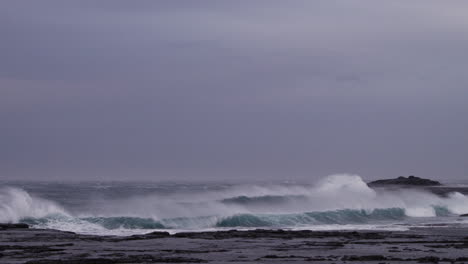 océano tormentoso con fuertes vientos marinos levantando el borde de las olas rompiendo en las rocas de una bahía