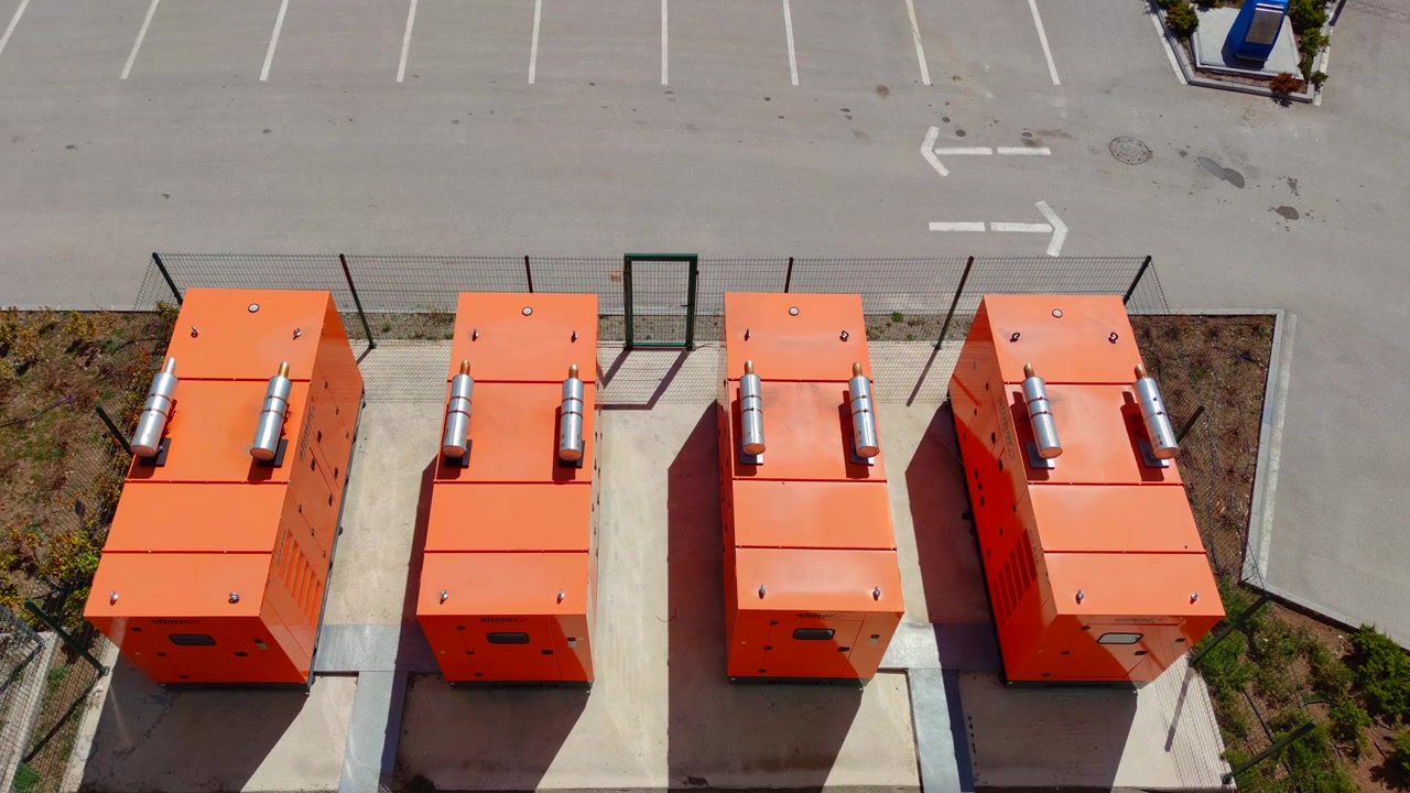 Aerial View of Four Industrial Orange Generators in a Parking Lot