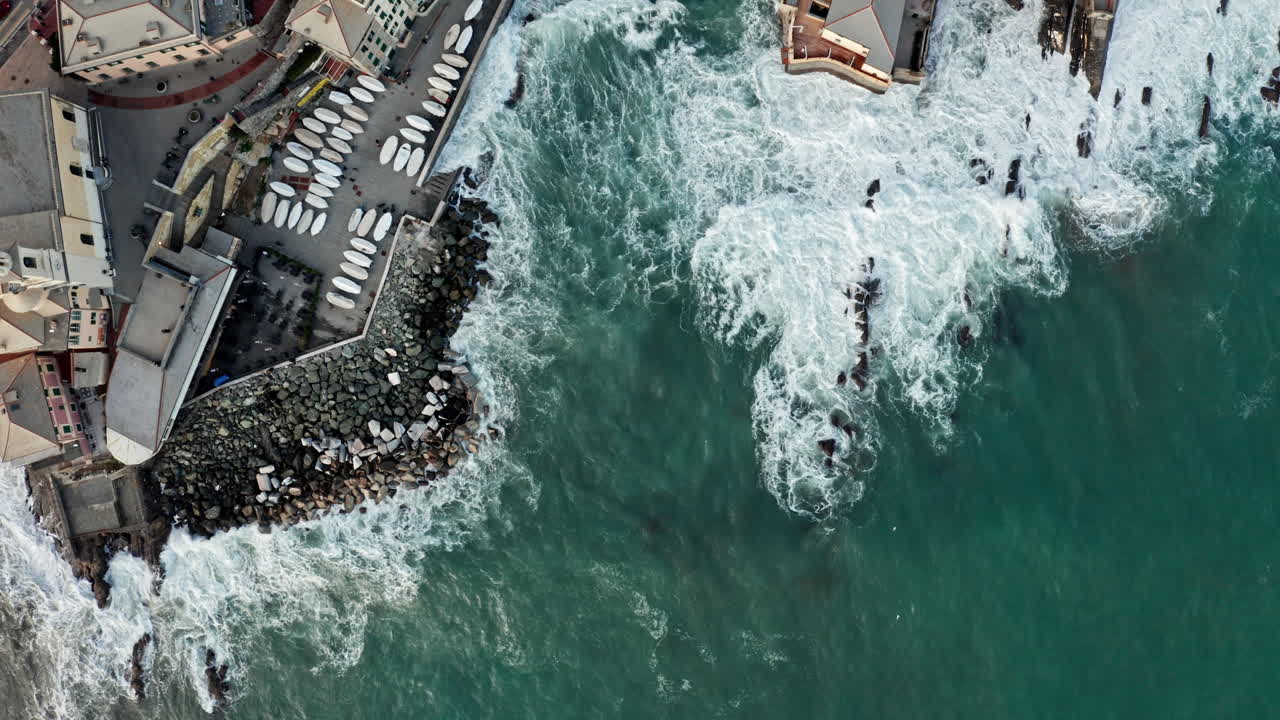 foto aérea de arriba hacia abajo de las olas que chocan contra la costa de génova y la playa de boccadasse