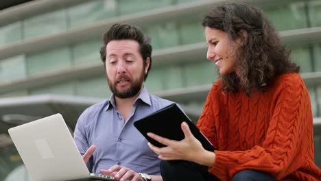 pareja que usa computadora portátil y tableta al aire libre