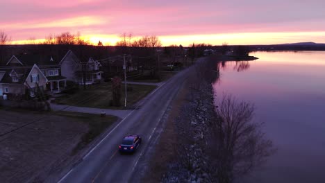 tracking drone shot of a car driving away in the distance at sunset.